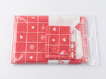 Mantel navideño rojo doblado junto a su empaque